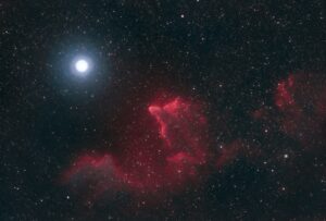 Une nébuleuse en forme de fantôme rouge à proximité d'une gigantesque étoile