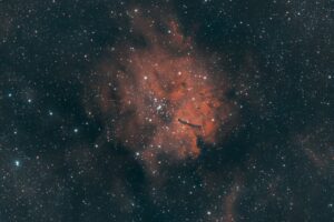 Une photo de l'espace qui montre une nébuleuse rouge sur un ciel étoilé