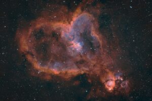 Une astrophotographie de nébuleuse en forme de coeur rouge et verte en forme de coeur sur un fond de ciel étoilé