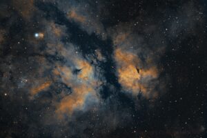 Une photo de l'espace qui montre une nébuleuse jaune bleuté en forme de papillon sur un fond de ciel étoilé