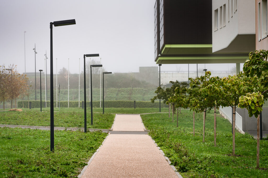 Campus Université de Lorraine – Metz Technopôle Chemin piéton bordé par des végétaux et par des lampadaires le long d'immeubles